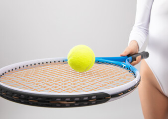 Slender woman in white bodysuit  plays tennis. The concept of sports and healthy lifestyle.