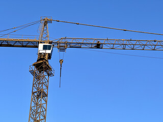 Tower crane against clear blue sky. Construction, urban development, industrial progress, engineering, infrastructure, building site, blue background, modern industry. 