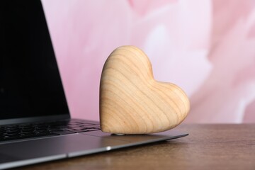 Wooden heart and laptop on table, closeup. Online dating site