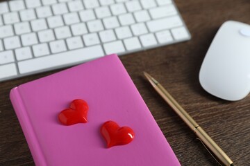 Decorative hearts, computer keyboard, mouse, notebook and pen on wooden table, closeup. Online...