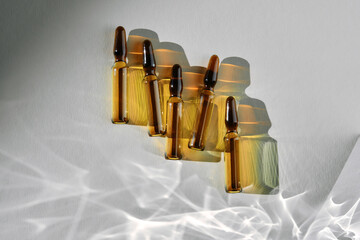 Ampoules on a gray background with stripes of shadows.