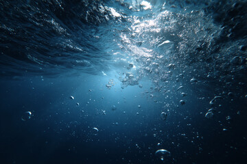 Underwater view showing rising air bubbles and sunlight penetrating the deep blue ocean water