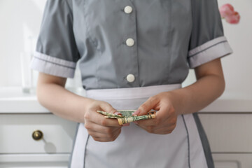 Chambermaid counting tips leaning chest of drawers in hotel room, closeup. Gratuity for work