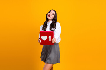 Bright and engaging photo of a cheerful young woman holding a red box with a heart icon against a...