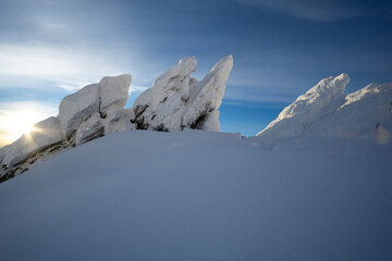Majestic snow-covered mountain peaks rise dramatically against a clear blue sky, illuminated by the...