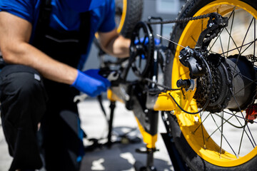 Bicycle repair technician working on yellow bike drivetrain during sunny day in urban setting