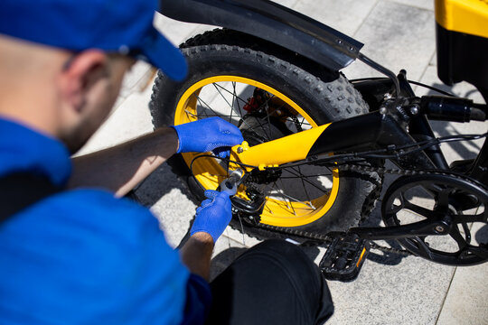 Bicycle mechanic repairing a yellow bicycle during daytime in an urban setting