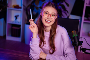 Podcaster woman in a casual sweatshirt broadcasting a live podcast with a microphone in a stylishly...