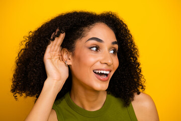 Attractive young woman with curly black hair gestures listening while smiling, showcasing beauty...