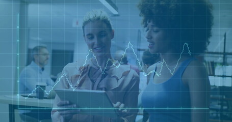 Two colleagues reviewing data on tablet in office, with coworker using laptop and chart overlay