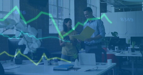 Collaborating professionals reviewing documents in open plan office, with laptop and floating data