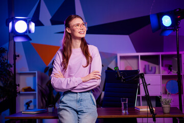 Young woman in a vibrant room with neon lighting preparing for a live podcast session or creative...