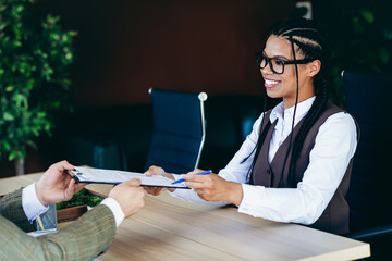 Confident businesswoman at a formal workplace analyzing documents and engaging in a professional...