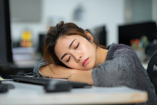 An Asian businesswoman naps at her desk in the office from exhaustion