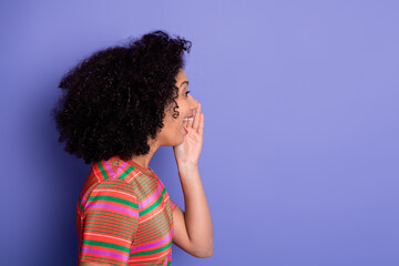 Side view of a young woman with curly hair laughing on a vibrant violet background, expressing joy...
