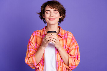Portrait of pretty young lady smell coffee cup wear shirt isolated on purple color background