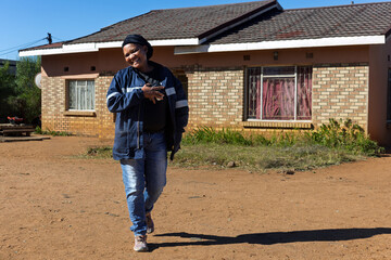 African village, single happy africa woman walking in the yard in front of the house , sunny morning