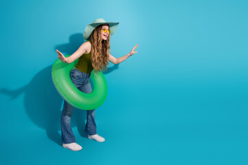 Stylish girl with green inflatable ring and summer fashion posing against vibrant blue background