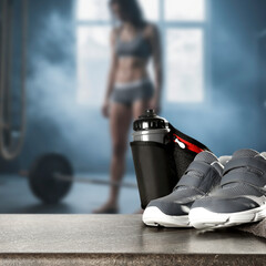 Sports shoes and water bottle with copy space. Blurred fit woman while intense strength workout in...