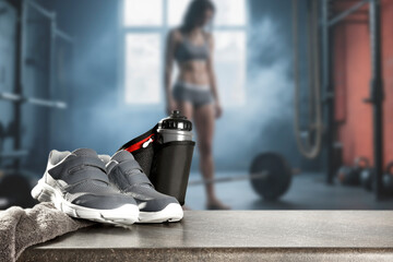 Sports shoes and water bottle with copy space. Blurred fit woman while intense strength workout in...