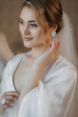 Elegant bride preparing for wedding ceremony in soft light with fine jewelry