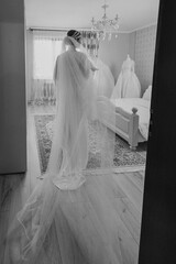 Bride preparing in her dress with a long veil in a bright, elegant room