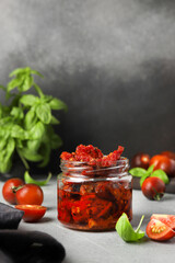 Jar of Sun-Dried Tomatoes in Olive Oil with Basil on Gray Background