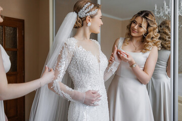 Bridesmaid assisting bride with wedding dress in elegant preparation moment