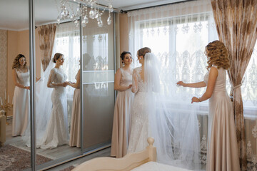 Friends help bride prepare for wedding ceremony in elegant indoor setting