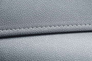 Close up of stitched leather texture. Gray surface with seam detail. Modern material background....