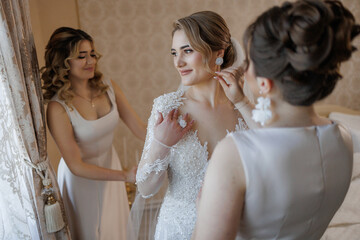Bridal preparations in a beautiful room with friends assisting in the final touches