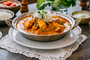 A close-up of a delicious, spicy chicken tikka masala garnished with fresh herbs