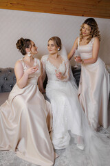Bridesmaids and bride celebrate with glasses during pre-wedding moments indoors in soft lighting