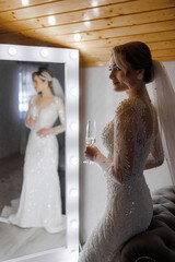 Beautiful bride in elegant dress admires herself in the mirror before the ceremony