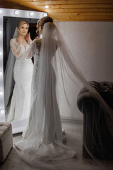 Bride preparing for wedding ceremony while viewing reflection in mirror at indoor venue