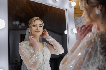 Bride adjusts her hairstyle before wedding ceremony in luminous dressing room mirror