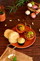 Luchi, Mix Vegetable and Dal Breakfast. Delicious indian meal featuring puri and curries served on a rustic wooden table