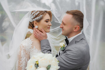 Couple shares a romantic moment under a veil during a wedding ceremony outdoors