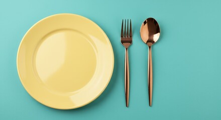 A flat lay of a pastel yellow plate with rose gold cutlery The setting is placed on a solid light teal background creating a vibrant and cheerful composition