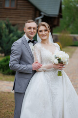 Elegant wedding couple poses outside a rustic venue during a sunny afternoon celebration