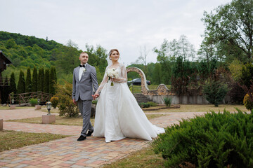 Joyful couple walks through garden after wedding ceremony in serene countryside setting