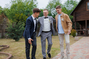 Three friends celebrate together in a garden setting during a wedding ceremony