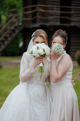 Bridesmaid and bride joyfully pose outdoors with bouquets during wedding celebration