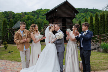 Couple kisses during outdoor wedding ceremony surrounded by joyful friends and family