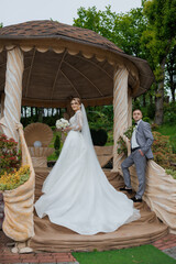 Couple celebrates wedding in garden gazebo surrounded by lush greenery and flowers