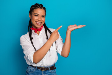 Smiling young woman with braids in a casual outfit gesturing on a blue background presenting...