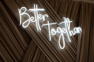 Inspirational neon sign illuminating a fabric backdrop in a cozy venue setting during an event
