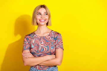Young woman with blonde hair in a stylish printed top smiles against a yellow background, exuding...