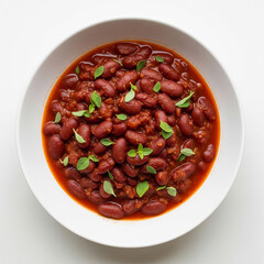 Overhead clean shot of glossy red beans in rich tomato sauce, garnished with fresh herbs in white bowl. Bright natural light copy