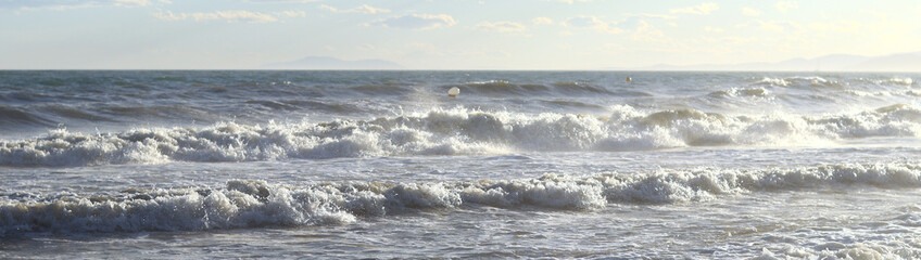 Waves on the sea. Banner. Photo of seascape. Waves with white foam. Natural background. Concept of seaside vacation, resort, rest